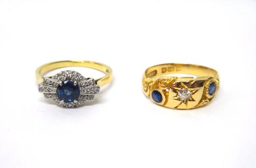 A gold and platinum, sapphire and diamond ring, in an Art Deco shaped cluster style, claw set with a circular cut sapphire to the centre and otherwise