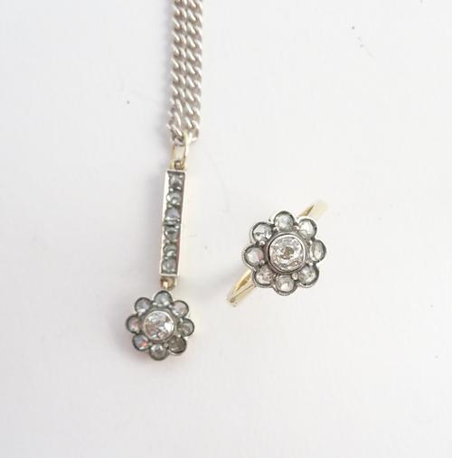 A diamond set cluster pendant, mounted with a cushion shaped diamond to the centre, in a surround of eight rose cut diamonds and with a row of six fur