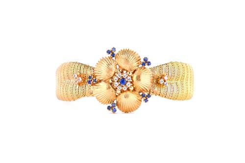 An 18ct gold, blue and colourless gem set bracelet, the front with a flowerhead shaped motif, the petals formed as five scallop shells, otherwise in a