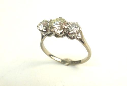 A white gold and platinum, diamond set three stone ring, claw set with the principal circular cut diamond at the centre, between two smaller circular