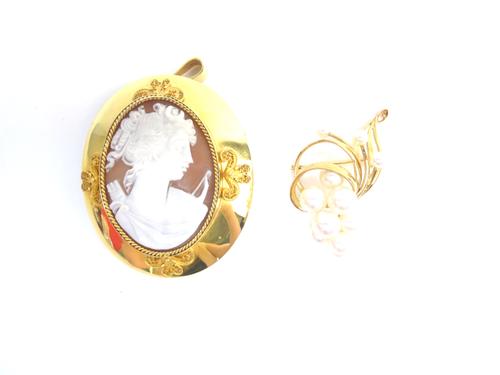 An oval shell cameo pendant brooch, designed as the portrait of a lady, in a ropetwist border, the wide mount with four filigree scroll motifs at inte