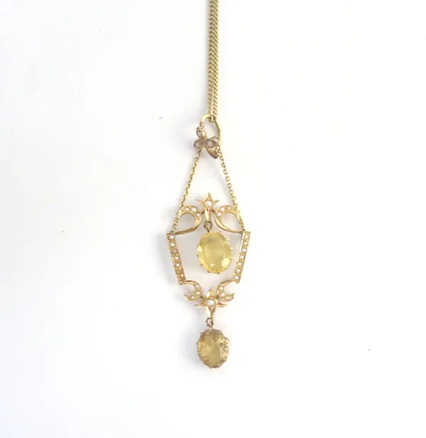 A gold, citrine and seed pearl pendant necklace, claw set with two oval cut citrines and otherwise set with seed pearls, in a pierced openwork design