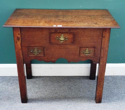 A George III and later oak lowboy, the shaped frieze with three drawers on canted block supports, 85cm wide x 75cm high x 46cm deep.  H5