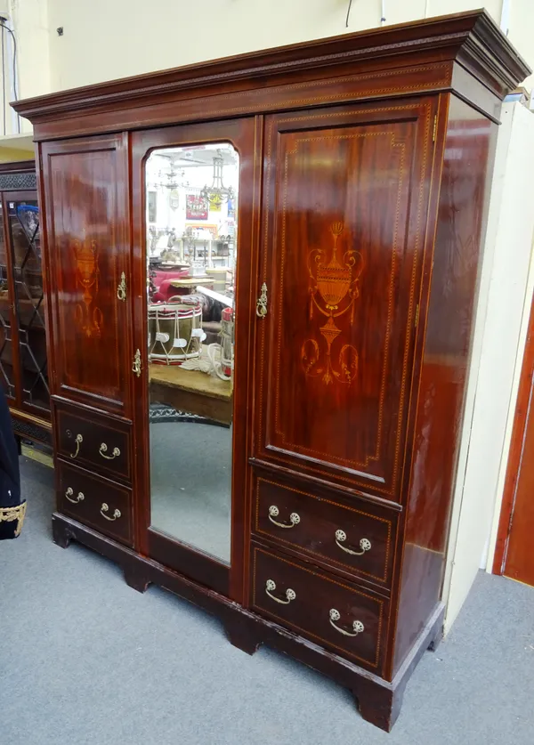 A late 19th century marquetry inlaid mahogany compactum wardrobe, with bevelled mirrored central door flanked by panelled cupboards and two short draw