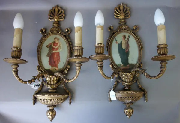 A set of four giltwood two branch wall appliques, early 20th century, each with anthemion cresting and an oval polychrome painted figural tin backplat