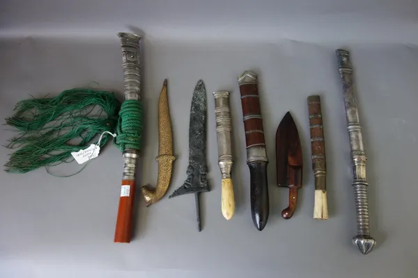 A Burmese shan knife, with steel blade, faux amber handle and ornate white metal mounts, 39cm long overall, four smaller shan knives, a small kukri an