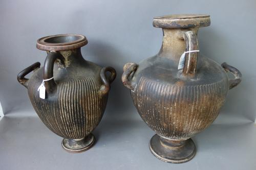 After the Antique, three large terracotta ewers, each of two handled form, with fluted decoration to the body on a circuar pedestal foot, the tallest