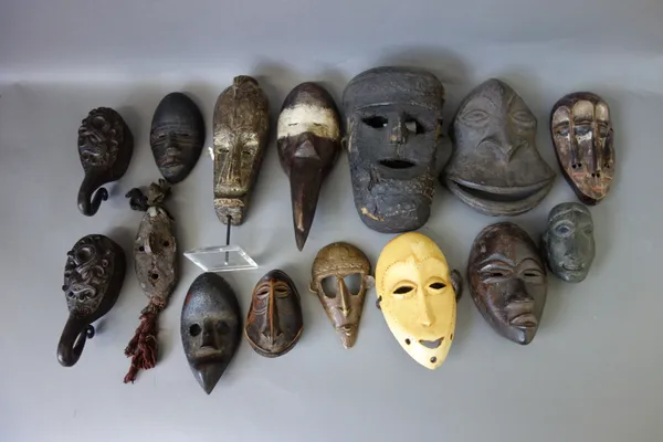 A quantity of African tribal wooden masks, similar brass and bone masks, a feathered African head ornament and related tribal items, (qty).