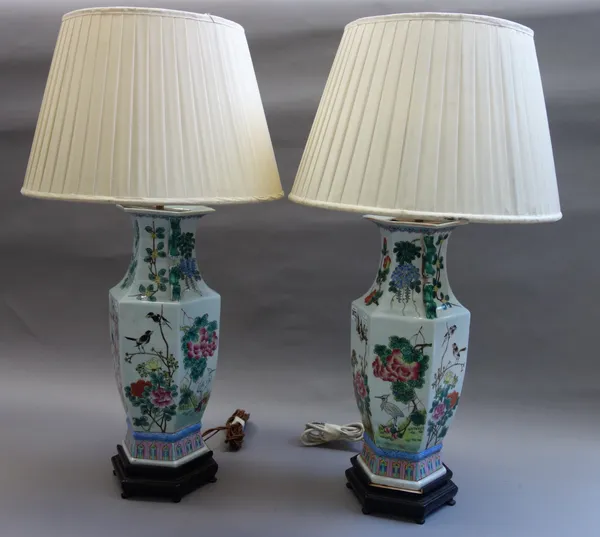 A pair of modern Chinese famille verte table lamps, each of two handled hexagonal form, on shaped wooden bases, with cream silk pleated shades, the va