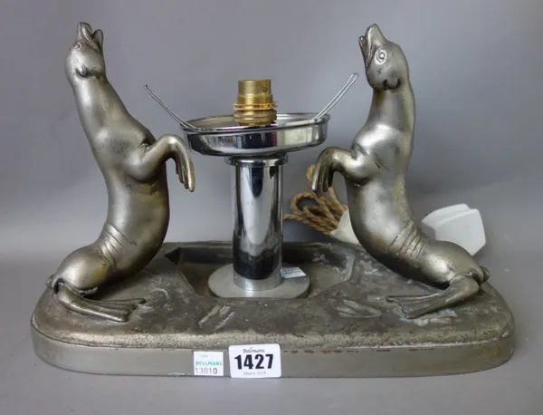 A white metal Art Deco table lamp cast with two opposing seals, a figural Art Deco table lamp, and one further cast with a stylised antelope atop a ma