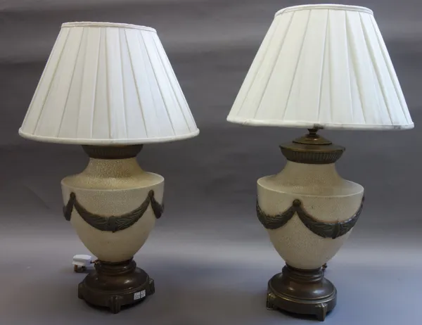 A pair of painted metal table lamps, modern, each of classical urn form, on a circular base with cream silk pleated shades, the lamps 42cm high, (2).