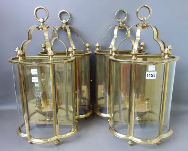 A set of four modern brass and glass wall lights, each with three shaped glass panels enclosing a two branch light fitment, surmounted with a loop han