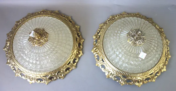 A set of seven gilt metal and moulded glass circular ceiling lights, modern, each domed glass shade supported by a pierced foliate frame, 29cm diamete
