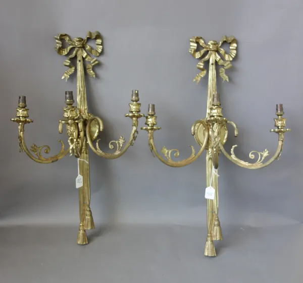 A set of six Victorian style gilt brass three branch wall appliques, modern, each with ribbon tied bow and backplate issuing three fluted branches, 64