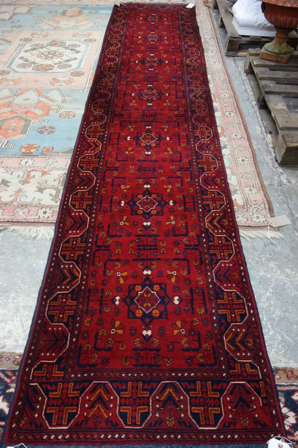 An Esari runner, the madder field with seven star compartment, a waved border, 402cm x 80cm.