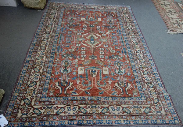 An East Persian rug, antique washed with red ground and allover design and an ivory border, 244cm x 168cm.