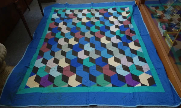 A Victorian style patchwork quilt, late 20th century, with multi-coloured deceptive squares within a wide blue border, 203cm x 180cm, and another more
