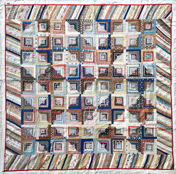 A Victorian style patchwork quilt, multi-coloured textile comprising overlapping concentric squares within an angled overlapping wide border, laid to