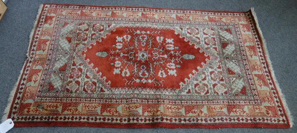 A Kerman rug, south east Persian, with cream medallion and red allover field, 140cm x 211cm, and a modern Turkish rug with red field, 93cm x 155cm, (2