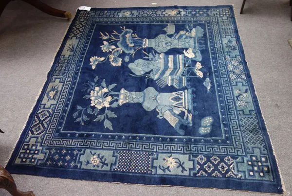 A Chinese rug, early 20th century, the blue field with vases and jardiniere in a foliate border, 184cm x 161cm.