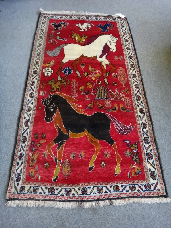 A modern Chinese rug, the red field with prancing ponies, 108cm x 200cm.