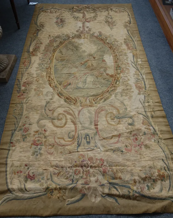 A late 19th century Aubusson tapestry, with central vignette of lovers in a woodland within foliate reef and festoon surround, 130cm x 251cm.