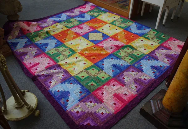 A modern patchwork quilt, comprising forty nine large coloured squares with integral coloured design, with a purple border and foliate backing, 250cm