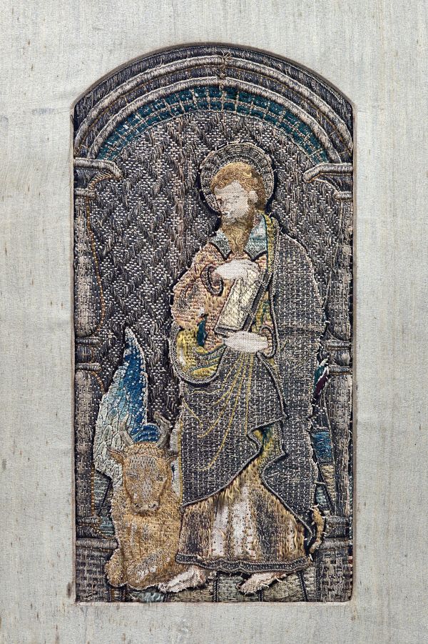 A stumpwork orphrey panel depicting St Luke, 17th century or earlier (a.f), framed and glazed, the panel 32cm x 16cm.  Illustrated