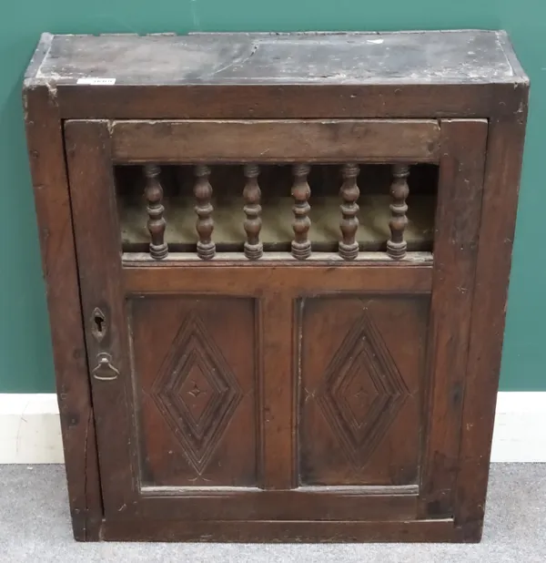 A 17th century oak hanging food cupboard, the single door with open turned decoration over pair of panels 69cm wide x 81cm high x 21cm deep.