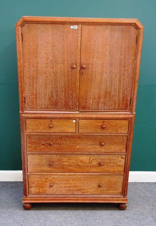 Heals, 101 Tottenham Court Road, London, a limed oak linen press, the pair of upper doors enclosing three linen trays, over two short and three long g