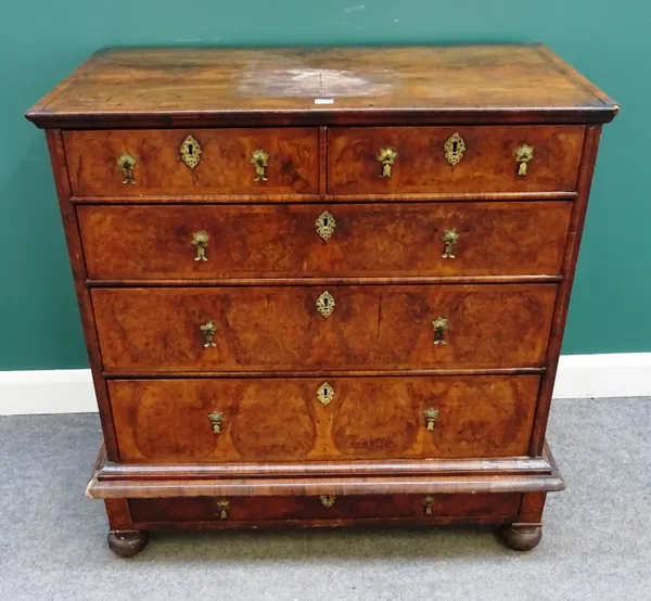 An early 18th century feather banded figured walnut chest on stand, of two short over three long graduated drawers, the base with one long drawer (red