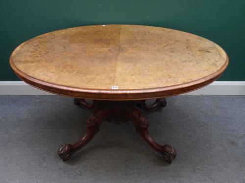 A Victorian marquetry inlaid figured walnut loo table, the oval snap top on carved column and four downswept supports, 103cm wide x 138cm deep x 72cm