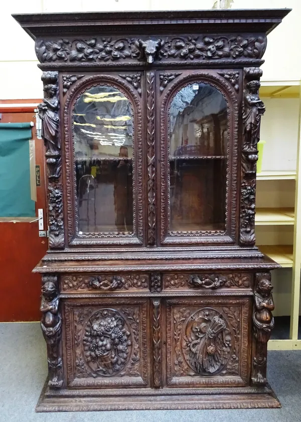 A 19th century German extensively carved oak display cabinet cupboard, with pair of upper glazed doors, flanked by female harvesting figures, the base