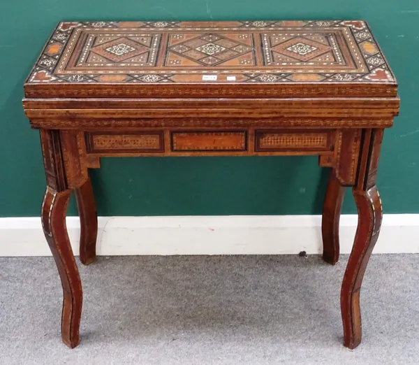 A late 19th century North African bone, mother of pearl and parquetry fold over card/games table, the stepped multi-function top on square section cab