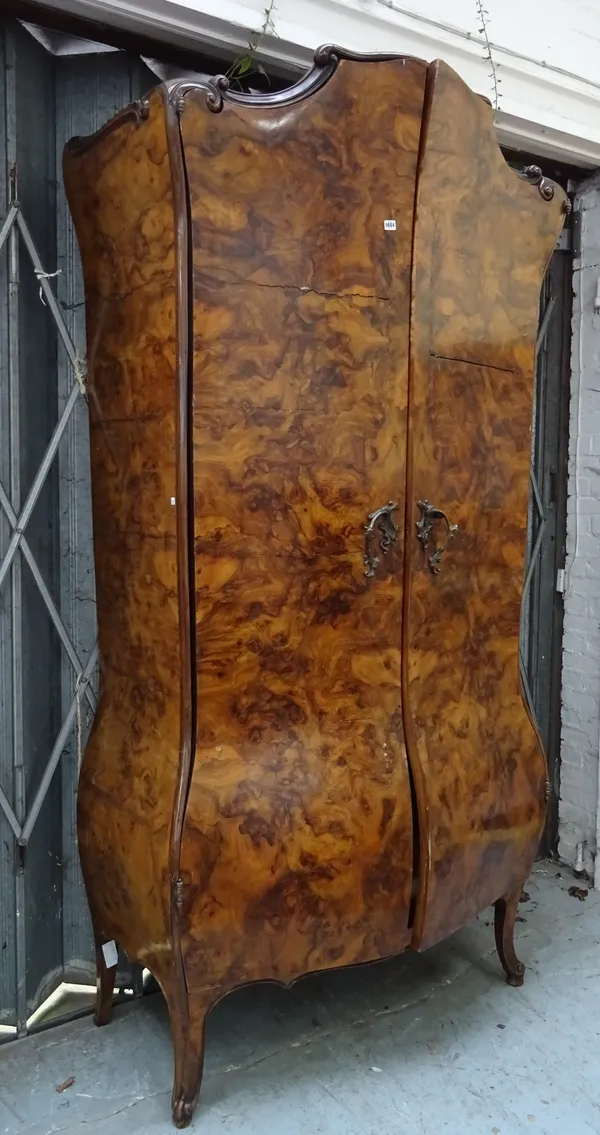An early 20th century Continental marquetry inlaid figured walnut armoire, the scroll cornice over a bombe two door base, enclosing single drawer, on