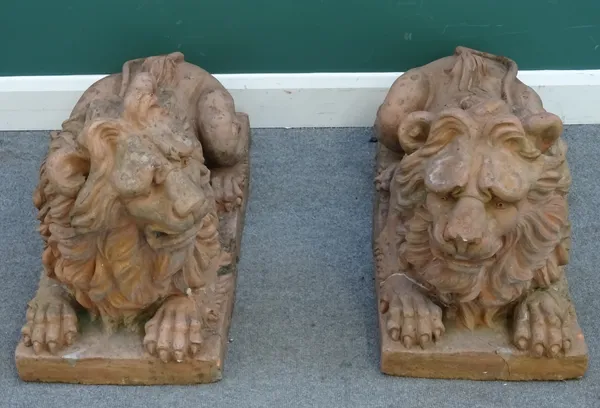 A pair of terracotta figures of recumbent lions, on rectangular bases, 85cm wide x 50cm high.