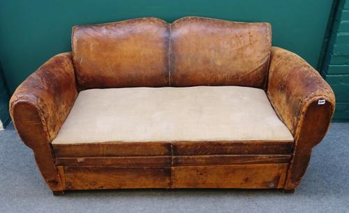 An early 20th century French brown lather upholstered sofa, with rollover arms and on block supports, 154cm wide x 86cm high.