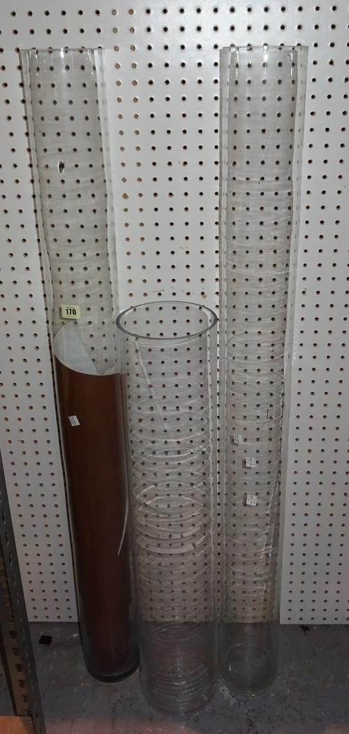 A group of three large cylindrical glass vases, the tallest 120cm, a silvered tin champagne bucket, a carved wooden bow with one handle, and two crack