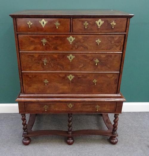 A William and Mary figured walnut chest on stand, later adapted to a drinks cabinet, on barley-twist supports, united by concave stretchers, 109cm, wi