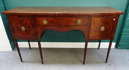 An early 19th century mahogany bowfront sideboard, with single drawer flanked by cupboards and deep drawer, on turned tapering supports, 184cm wide x