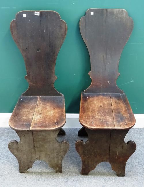 A pair of George III oak hall chairs, with shaped backs and solid seats, on slab supports, (2).