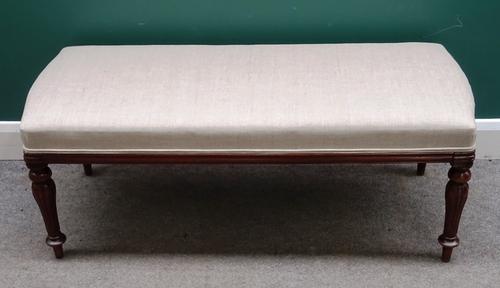 A mahogany framed footstool, the rectangular overstuffed top with bow short ends, on baluster reeded supports, 116cm wide x 48cm high x 46cm deep.