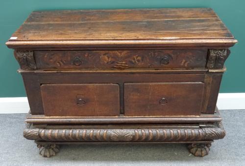 An 18th century Italian oak side cabinet, with one long and two short drawers and heavy gadrooned frieze, incorporating a secret drawer, on shaped bun