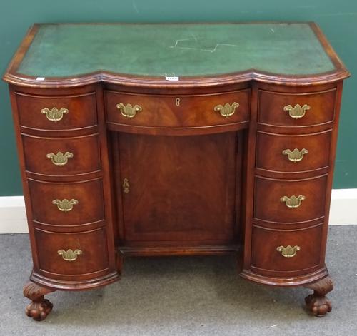 An early 18th century style mahogany kneehole writing desk, the triple bow top above nine drawers about the cupboard on claw and ball feet, 91cm wide