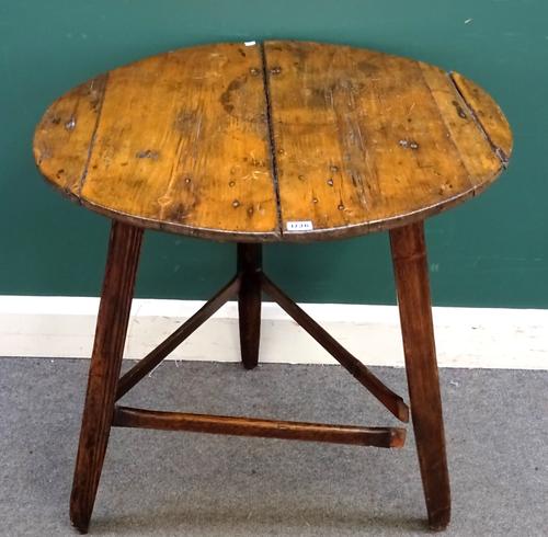An early 19th century and later pine cricket table, the circular plank top on three faceted supports, united by stretchers, 76cm diameter x 71.5cm hig