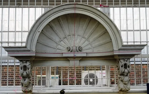 A late 19th/early 20th century white painted external over door, with concave shell centre flanked by cherub mounted scrolls, 188cm wide x 129cm high.