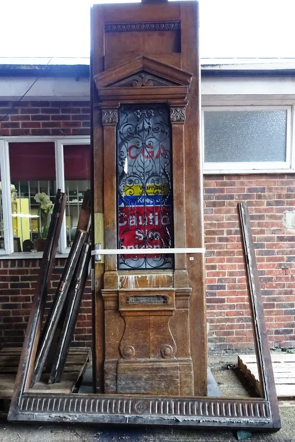 An extremely large pair of oak external doors and frame, each with raised architectural mouldings and wrought iron mounted glazed panels, the doors, 1