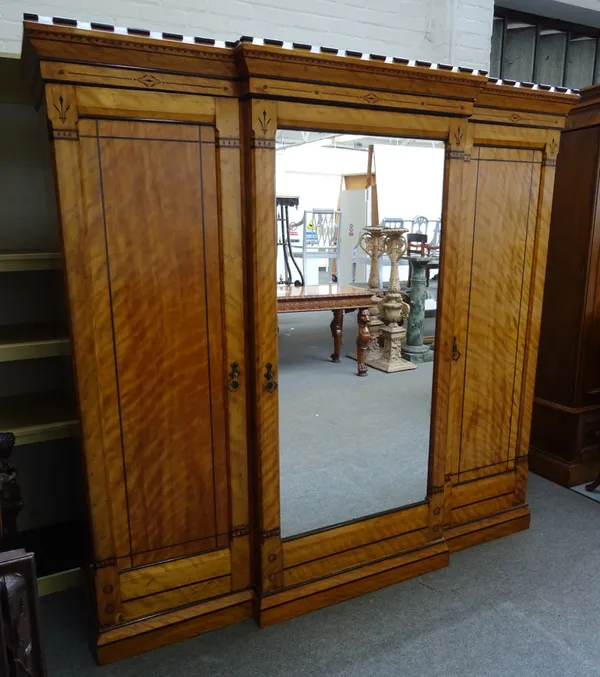 In the manner of J.P Seddon, a Victorian Gothic Revival inlaid satin birch breakfront triple wardrobe, with castellated cornice and mirrored central d