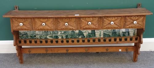A late 19th century Continental pine and mixed wood hanging spice rack, five drawers above a green and white printed tile back, shelf and hooks below,