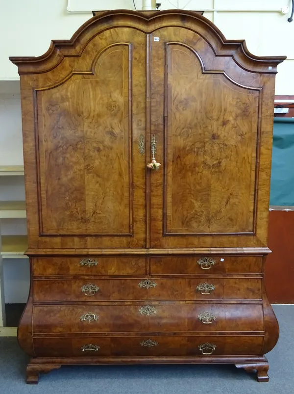 A late 18th century Dutch walnut linen press, the bonnet shaped top over a pair of panelled doors, the bombé base with two short and three long gradua